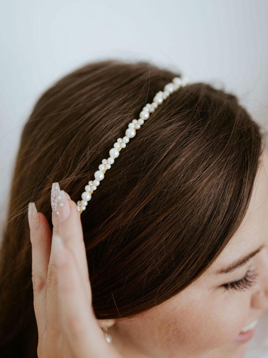 A close up photo of model wearing a thin pearl bridal headband, showcasing a simple yet elegant accessory perfect for adding subtle sparkle to any bridal hairstyle. Ideal for understated, romantic wedding looks.
