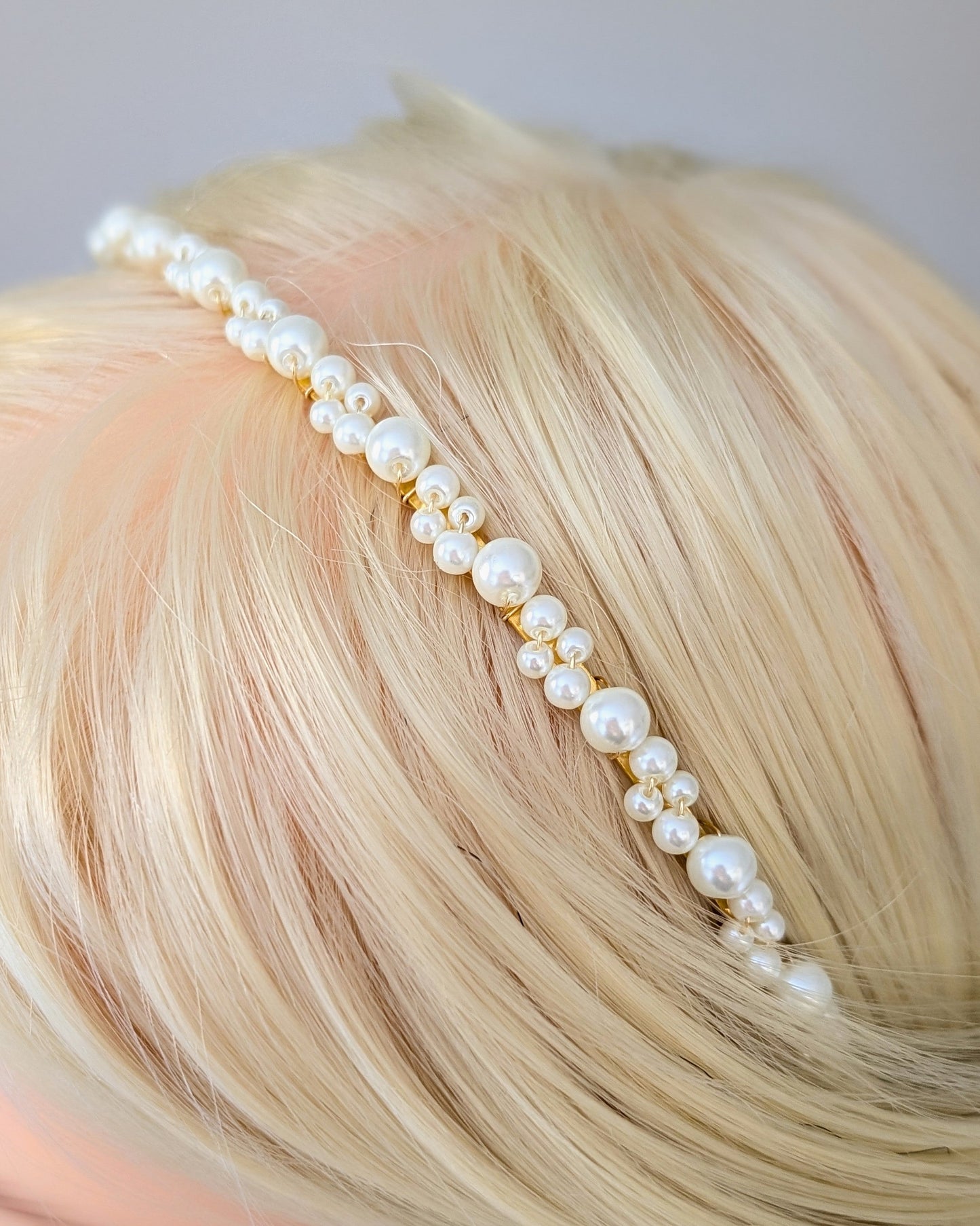 Pearl headband on a mannequin head with blonde hair against a gray background
