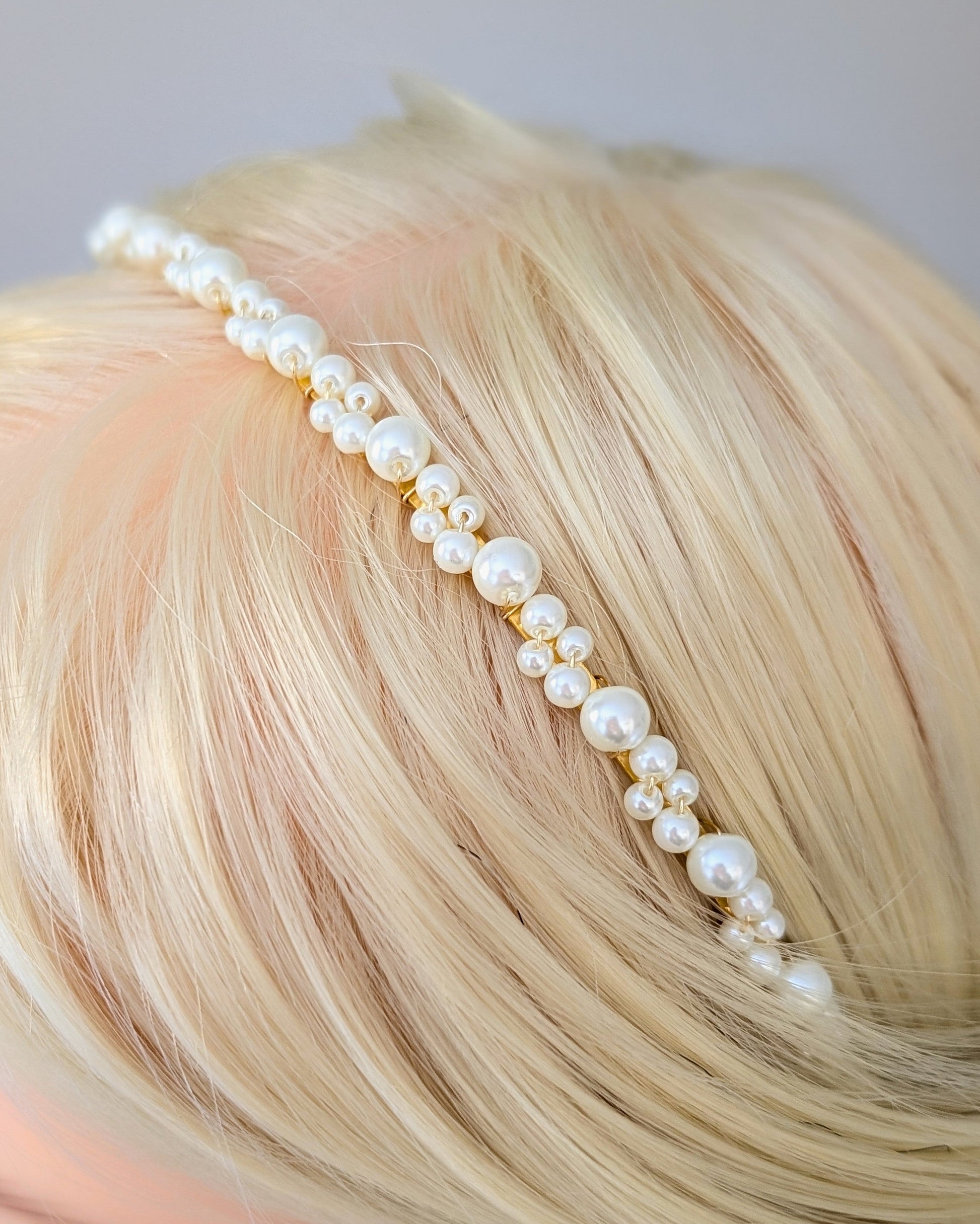 Pearl headband on a mannequin head with blonde hair against a gray background