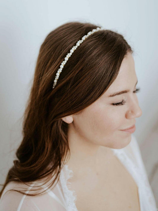 Model with textured waves wearing a thin pearl bridal headband, showcasing a simple yet elegant accessory perfect for adding subtle sparkle to any bridal hairstyle. Ideal for understated, romantic wedding looks.