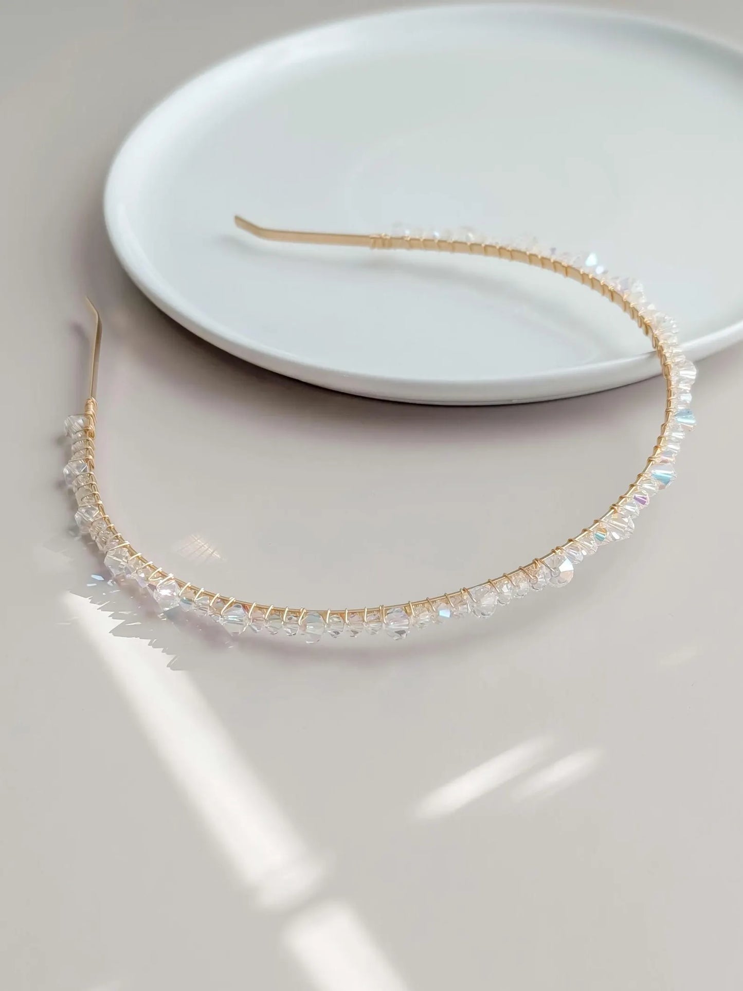 Gold headband with AB crystals on a white plate