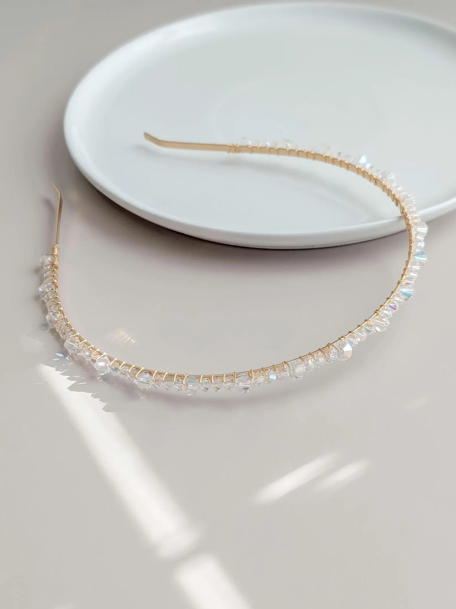 Gold headband with AB crystals on a white plate
