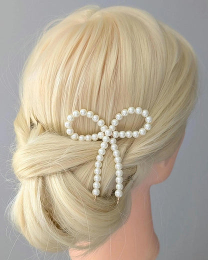 Blonde hair styled with a pearl bow accessory on a gray background