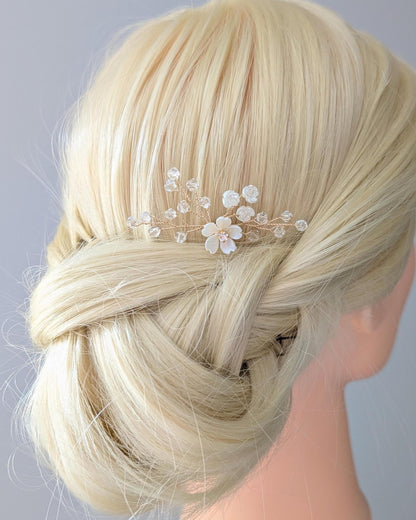 Blonde hair styled in an updo with a decorative floral and crystal branch hairpin on a mannequin head against a gray background