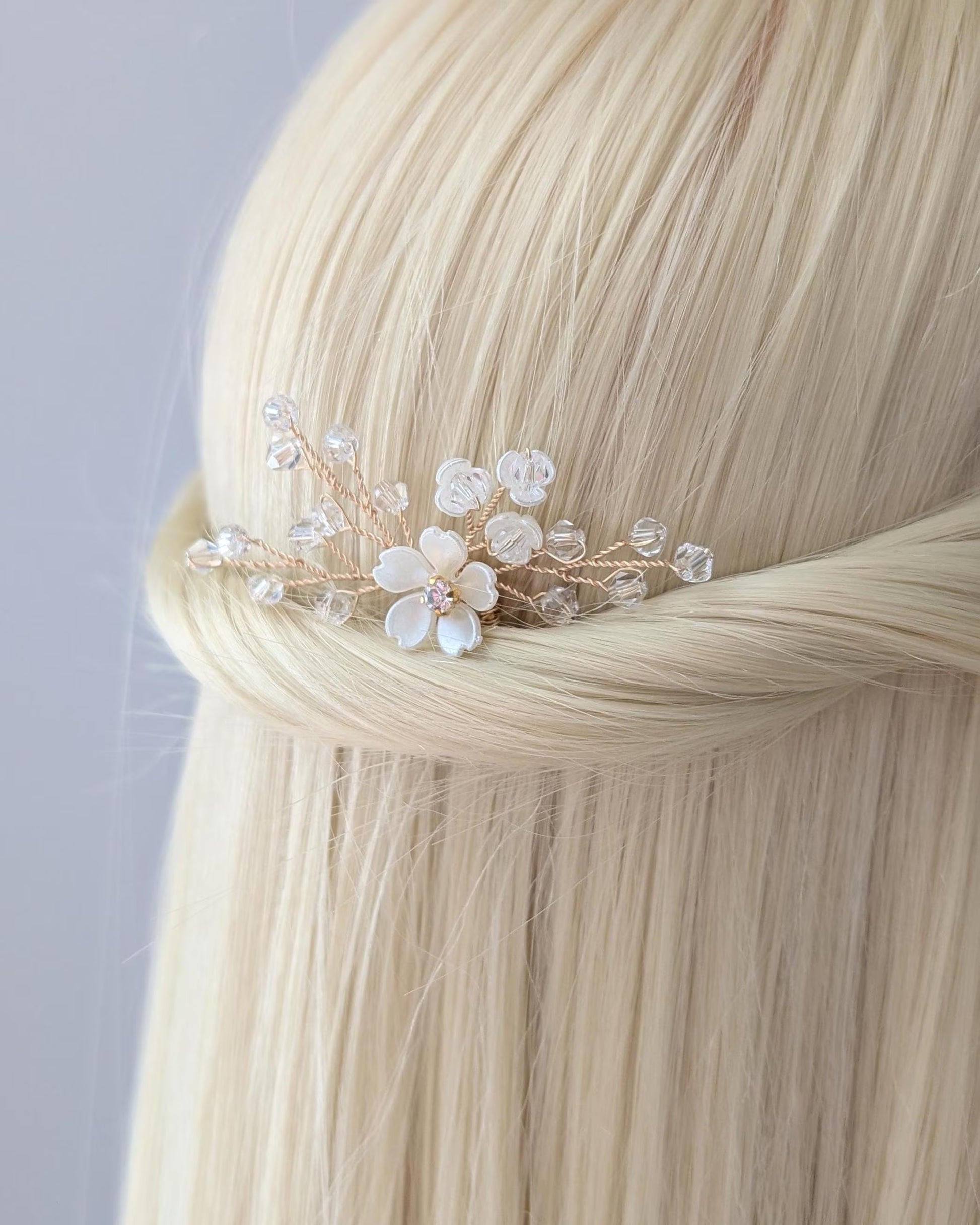 Hair accessory with flowers and beads on a person with blonde hair against a light gray background