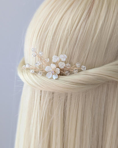 Hair accessory with flowers and beads on a person with blonde hair against a light gray background